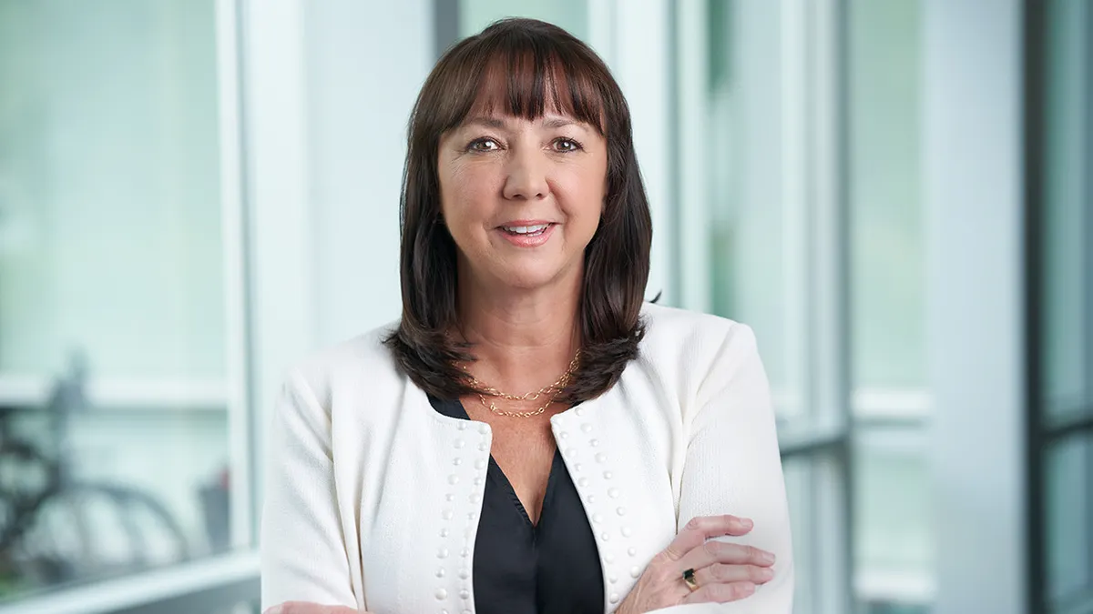 A woman in business attire stands outside a conference room