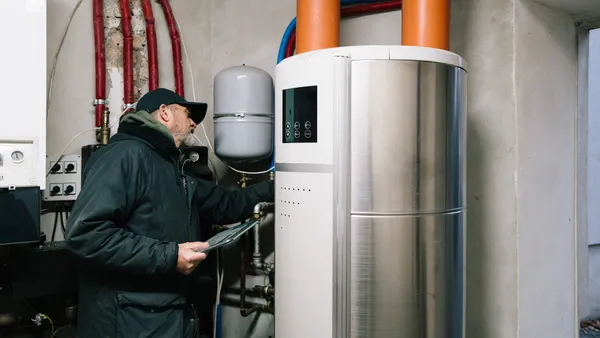 A technician inspects an electric hot water heater.