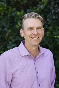 Headshot of a man in a pink shirt