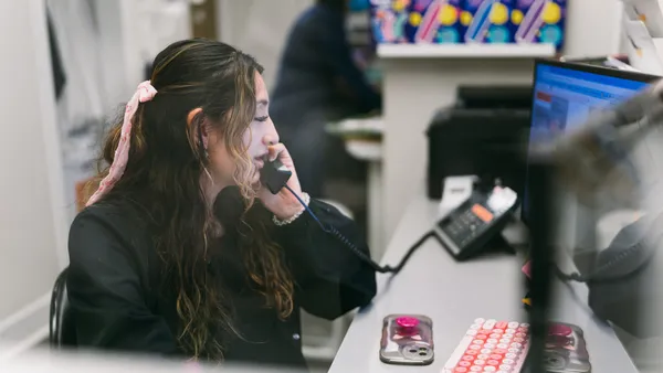 Secretary talks on the phone while working at her desk.