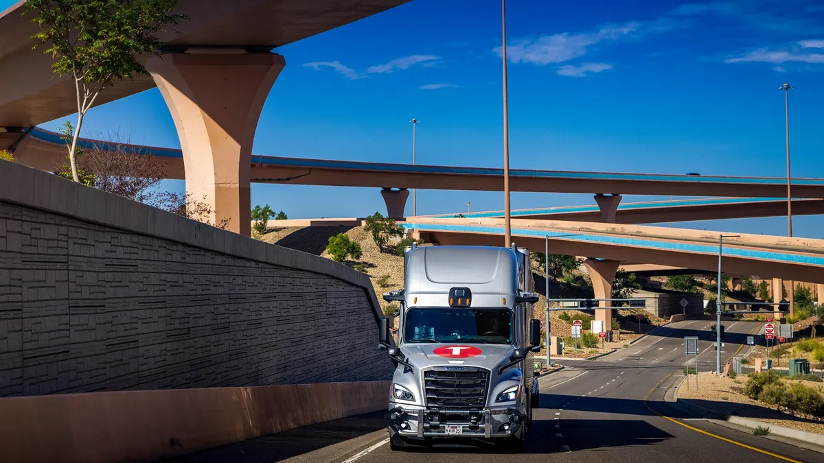 A Torc Robotics self-driving tractor-trailer being tested on a road under overpasses in New Mexico.