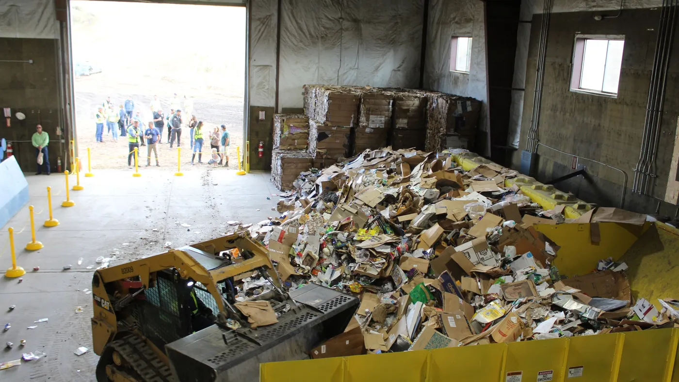 an overhead shot of people standing near the open door of a recycling facility.