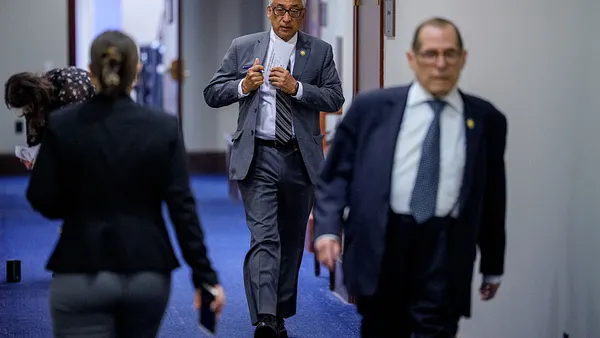 Three people are walking down a hallway in different directions.