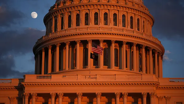 The moon is visible behind the U.S. Capitol building.