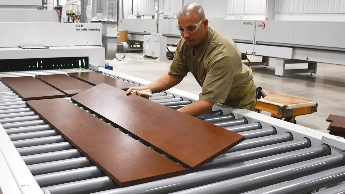 Factory worker putting wooden materials on machinery