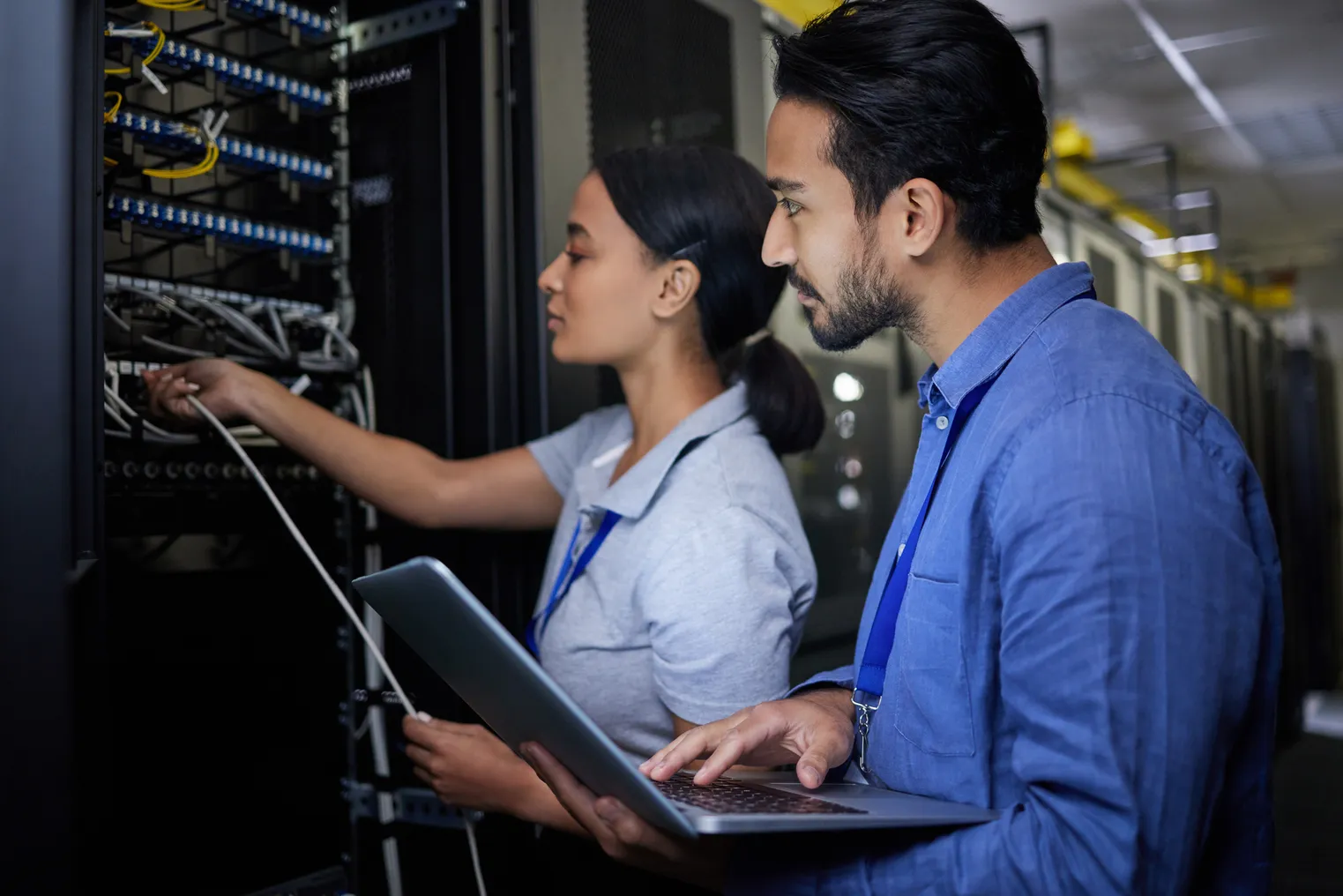 People examining a computer server with a laptop