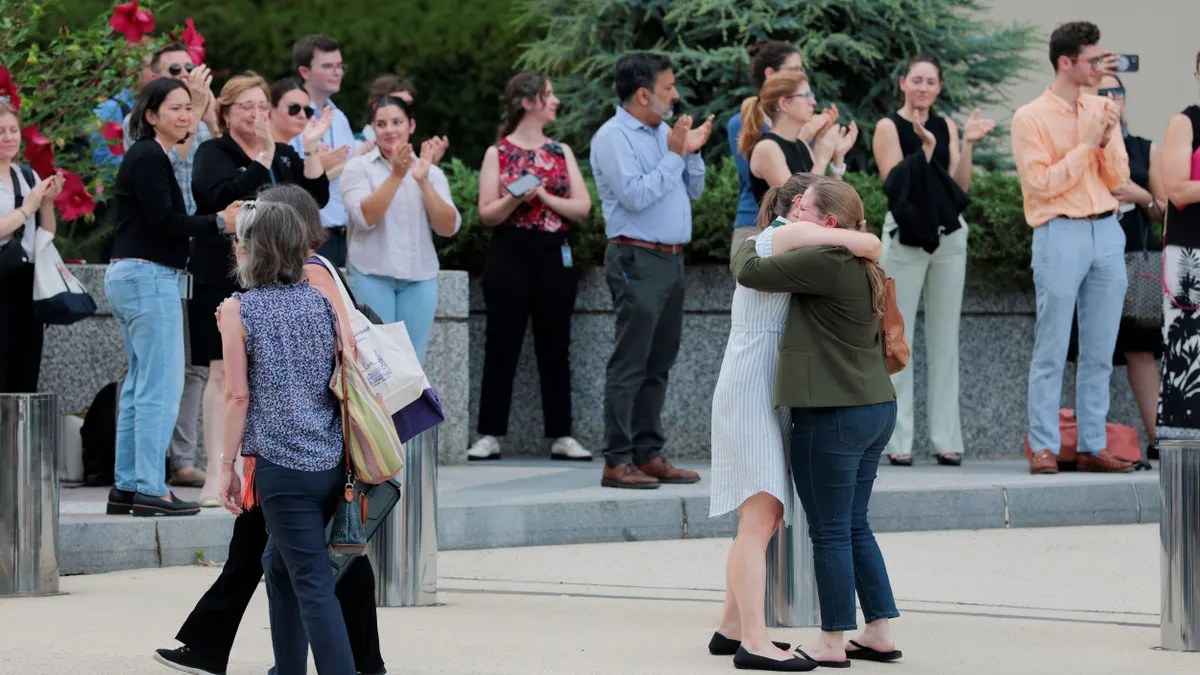 Employees clap for laid-off co-workers as they exit the building.