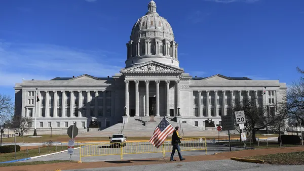 A man waves an American flag as he walks outside the Missouri State Capitol building in Jefferson City.