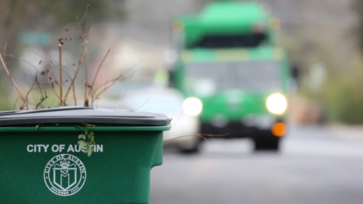 A waste collections bin with a collections truck in the background.