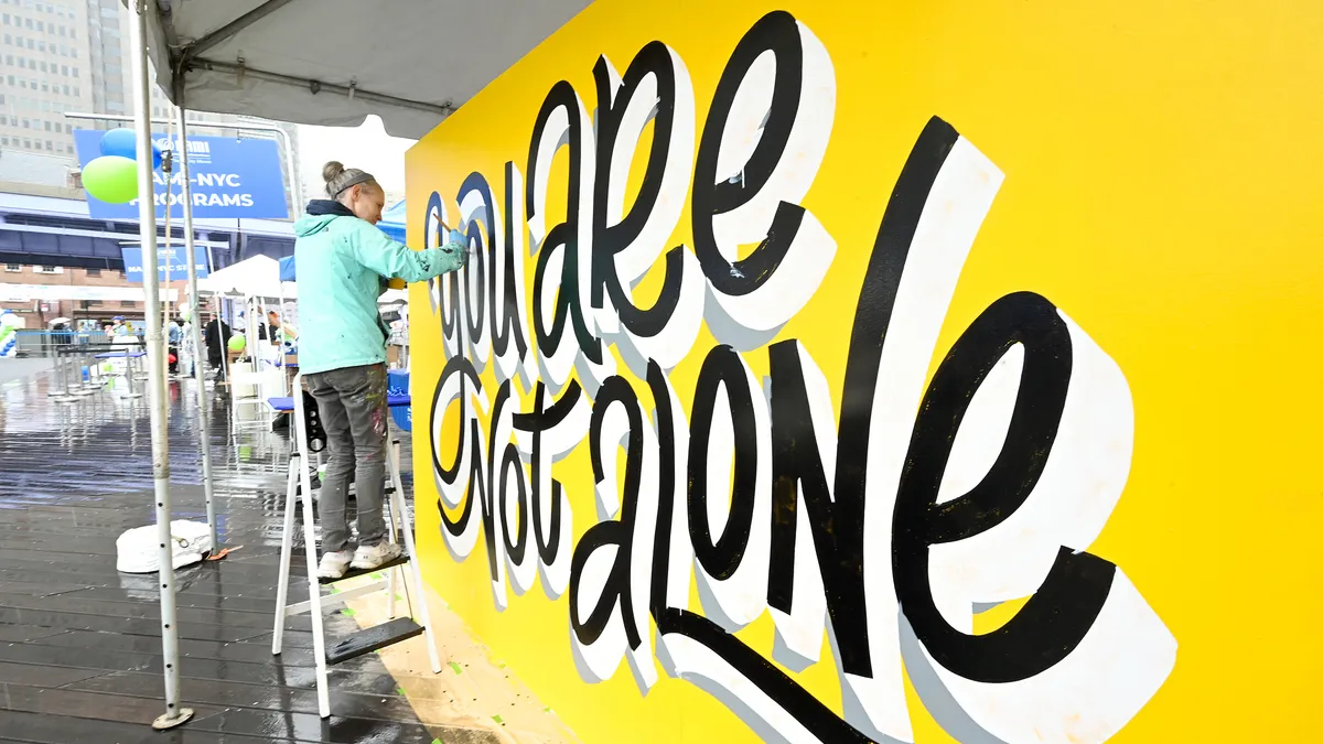 An artist paints a "You Are Not Alone" mural at a mental health awareness event in New York City.