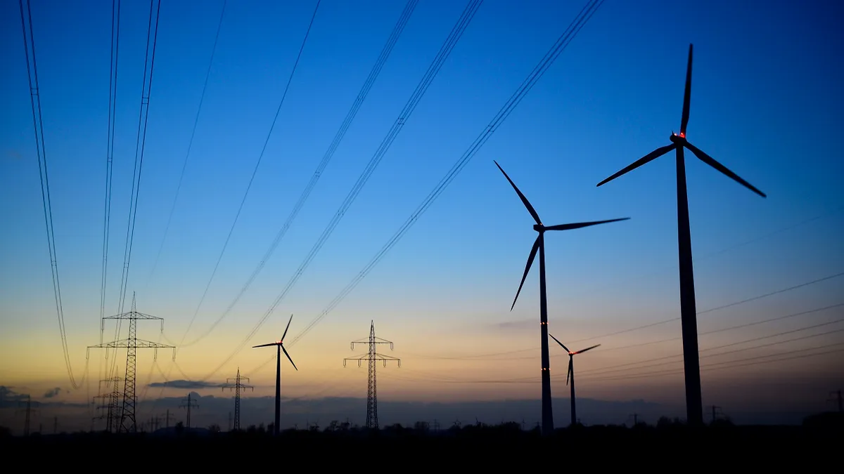 Power lines and wind turbines are seen at dawn.