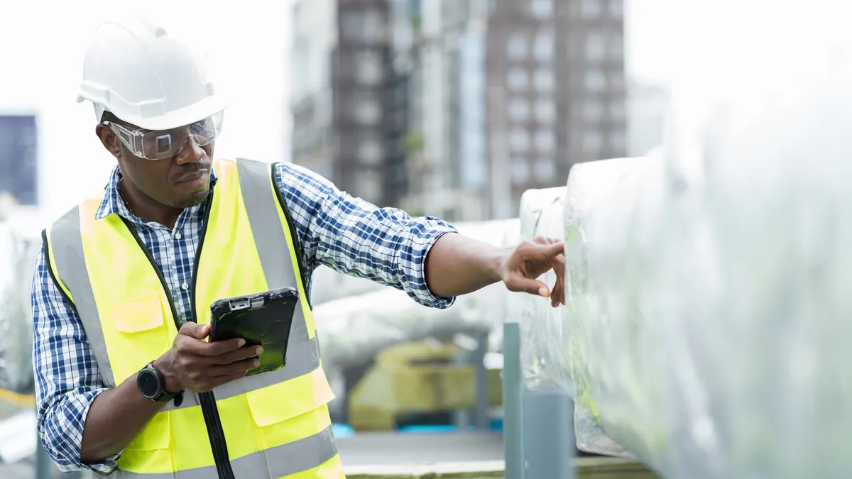 An engineer checking a maintenance pipe system for ventilation and air conditioning on the rooftop of a building.