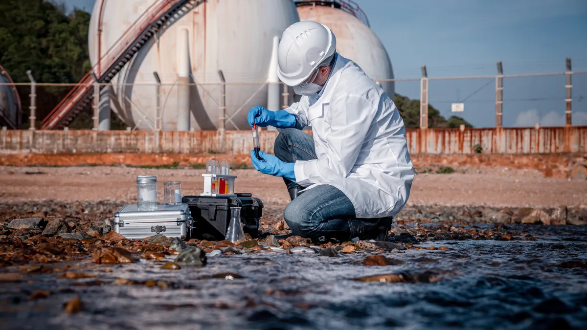 Scientist wearing safety uniform and glove under working water analysis and water quality by get waste water to check case in laboratory is environment pollution problem.