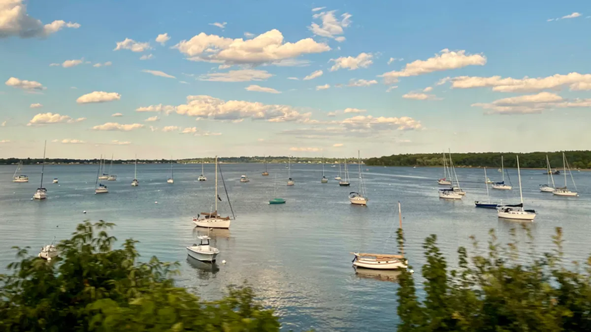 A view of boats on water in a Rhode Island bay, with blue skies and clouds