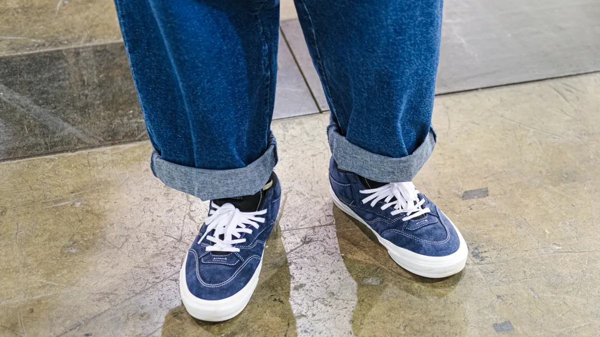 A close up of a person's rolled up jeans and sneakers. The sneakers a Vans in denim.