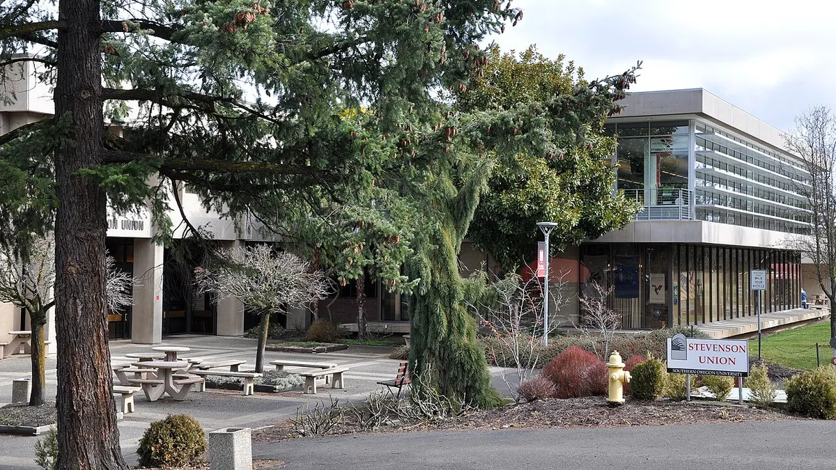 Modern brutalist building with picnic tables outside in foreground.