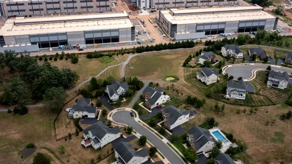 An aerial view of house near large warehouse-like buildings.
