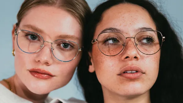 A closeup as two people in wire-frame glasses pose for the camera.