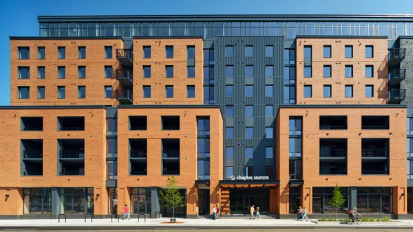 A mid-rise apartment building with a red brick and glass exterior.