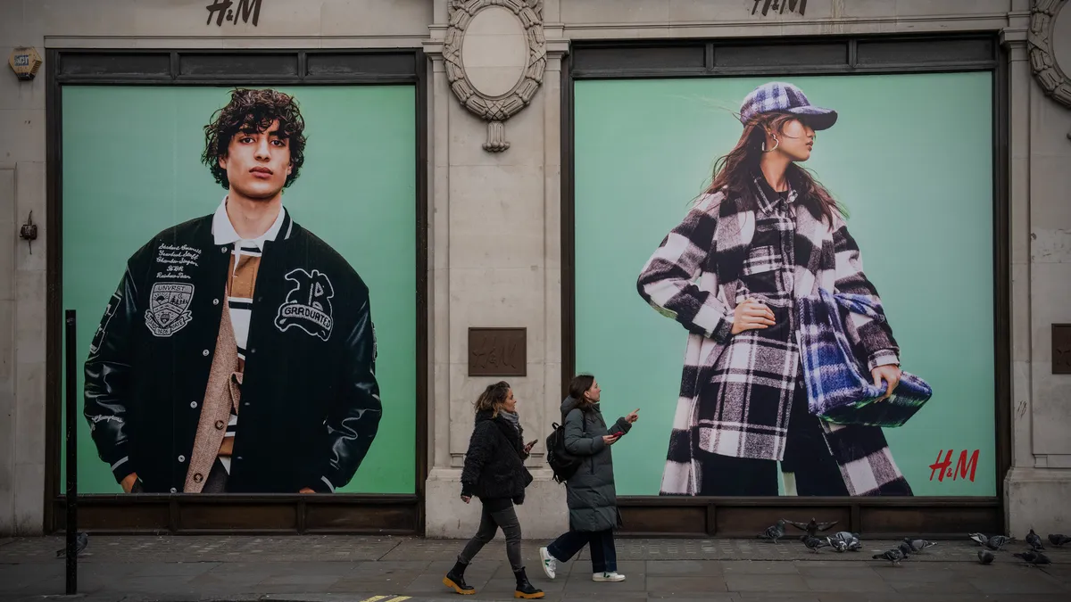 Two people walk by an H&M store in London.