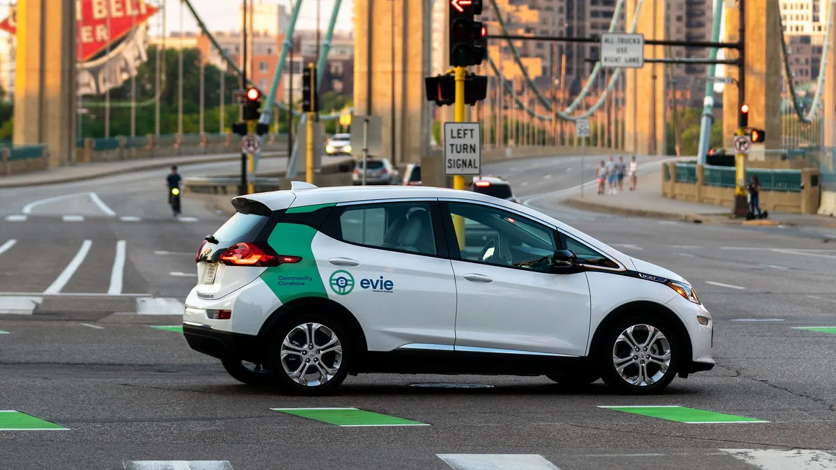 White car that says "Evie/Car Share" parked in front of a bridge.