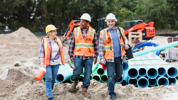 Three diverse construction workers walk on a jobsite.