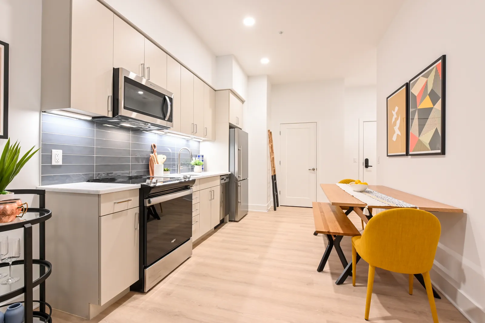 A white room with kitchen appliances and a picnic bench-style table.