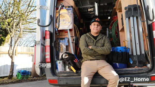 A man poses for a photograph in the back of a utility van.