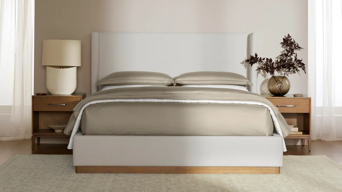 A bed in the middle of the room featuring a bed frame from Boll & Branch's new furniture collection.