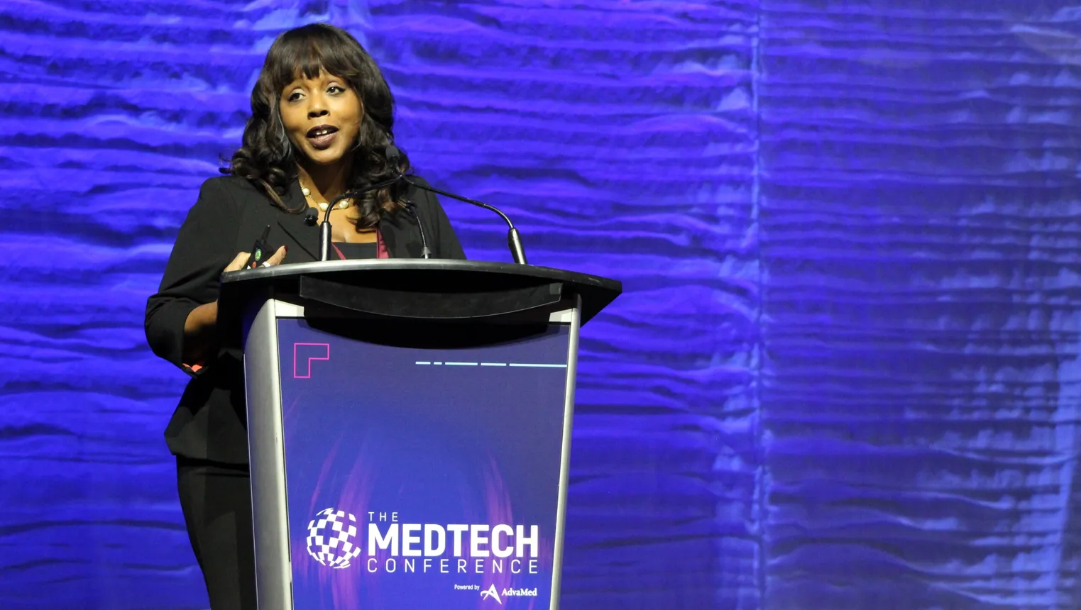 A person speaks at a podium on a stage.