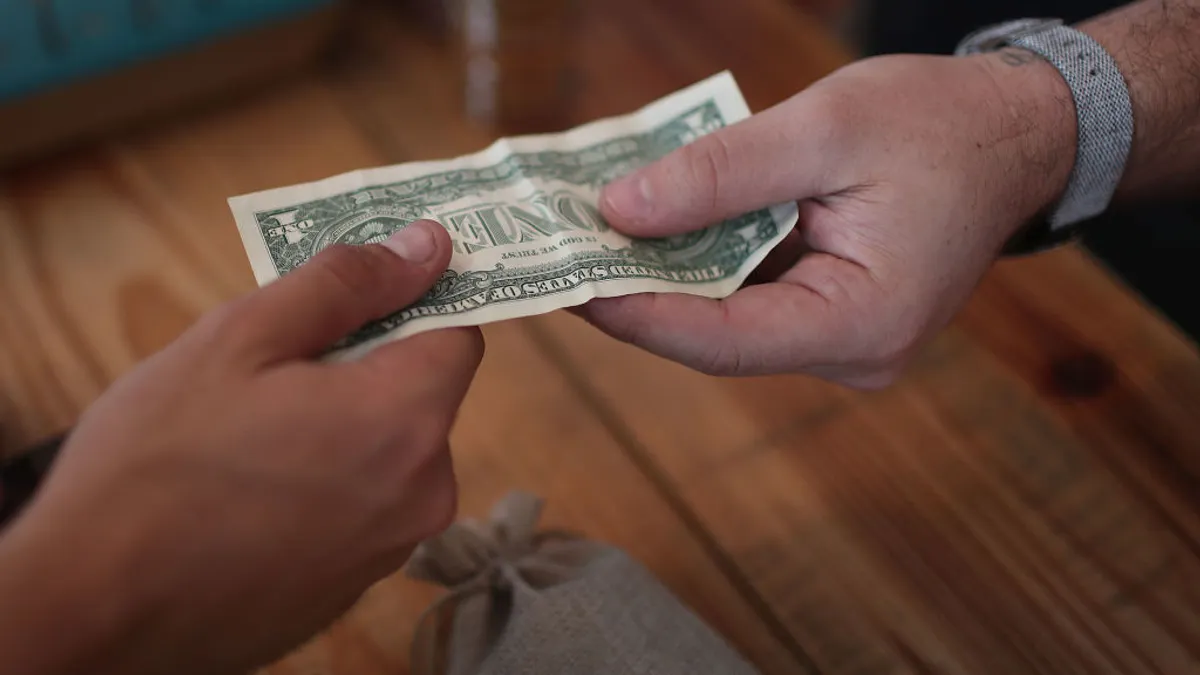 Dollar exchanged between hands at checkout counter