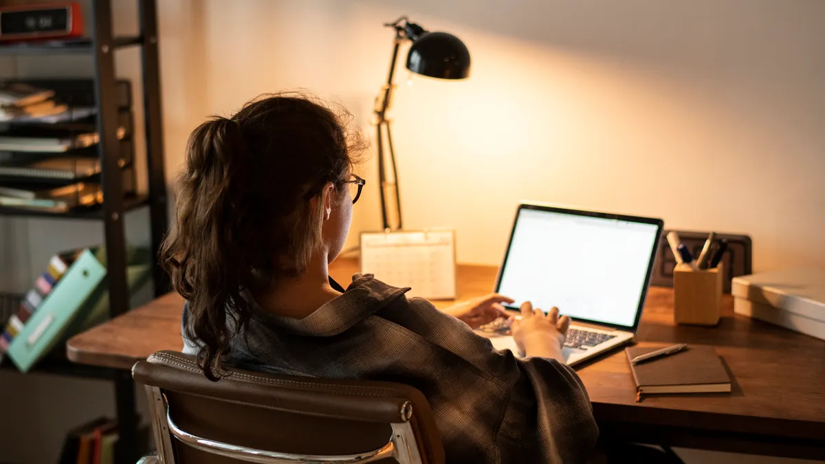 A young woman does homework on her laptop.