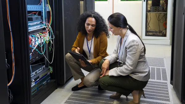 Adult women in data center checking cables and whole network, server setup and programing mainframe through digital tablet.