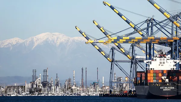 Shipping containers are stacked on a container ship at the Port of Los Angeles, as a truck passes above in front of the snow-capped San Gabriel Mountains, on February 7, 2023 in Los Angeles.