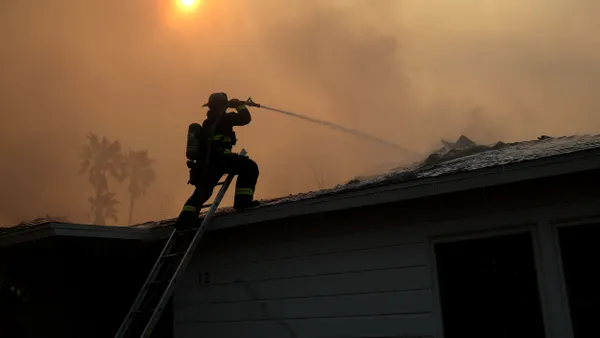 A firefighter sprays water on a burning home