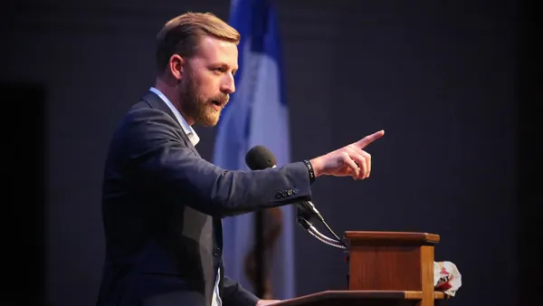 Top Oklahoma education official Ryan Walters speaks at a podium with his hand raised