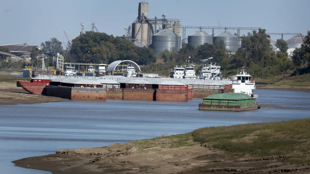 A tug pulls a barge into the middle of a river