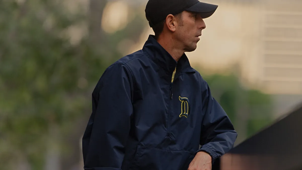 Guy Marino wears a blue jacket and a baseball cap and stares off the side of a bridge.