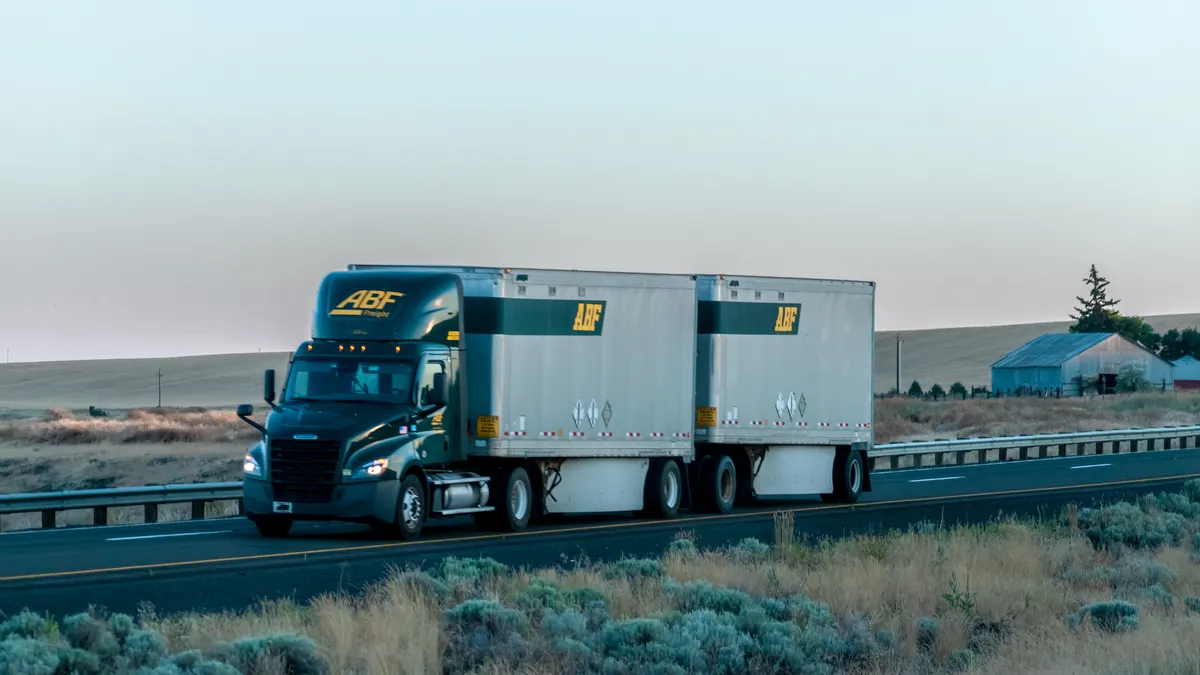 An ABF Freight System semi-truck with a double combination with fields in the foreground and background.