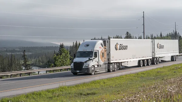 A Bison Transport double trailer with a mountainous scenery in the background.