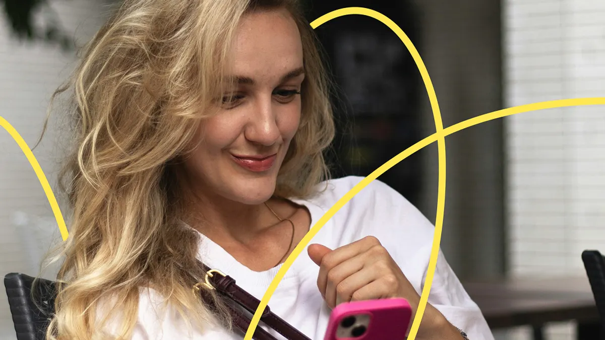 A woman with long blonde hair smiles while looking at her phone, seated outside. She wears a white shirt, and abstract yellow lines overlay the image.