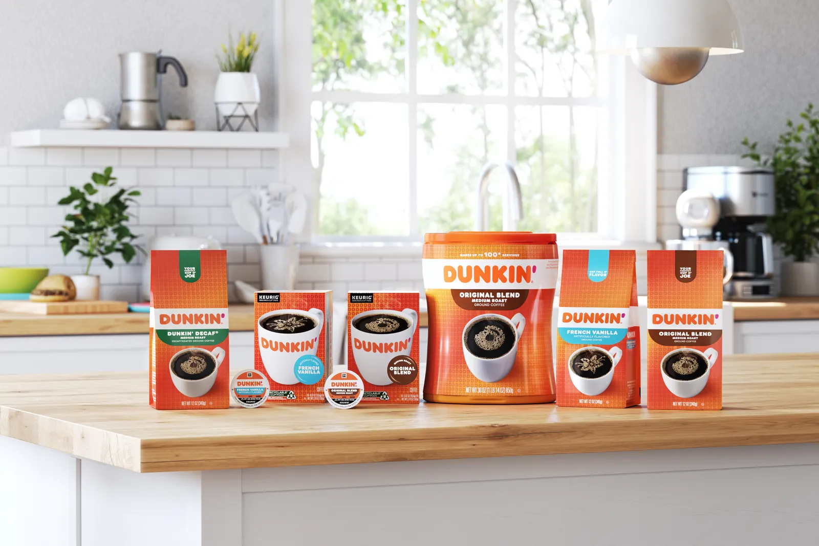 A lineup of Dunkin' coffee CPG products, including beans, grounds and K-Cup products, on a wooden countertop in a fairly white kitchen.