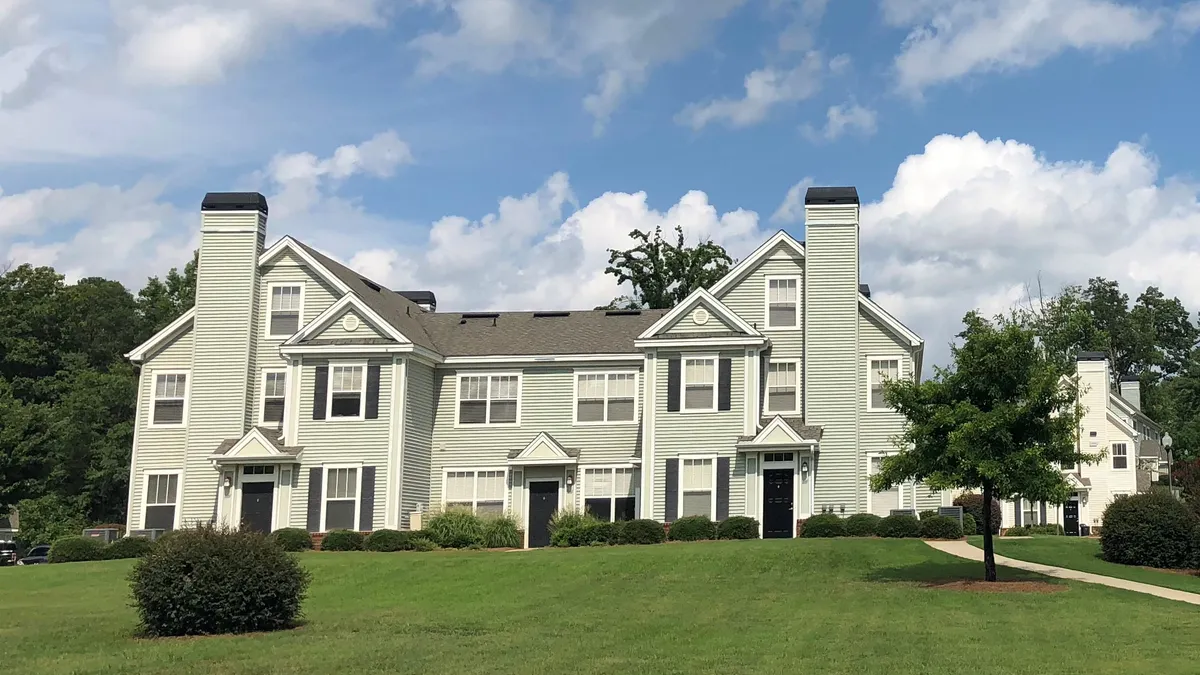 White apartment building with grass in the foreground.