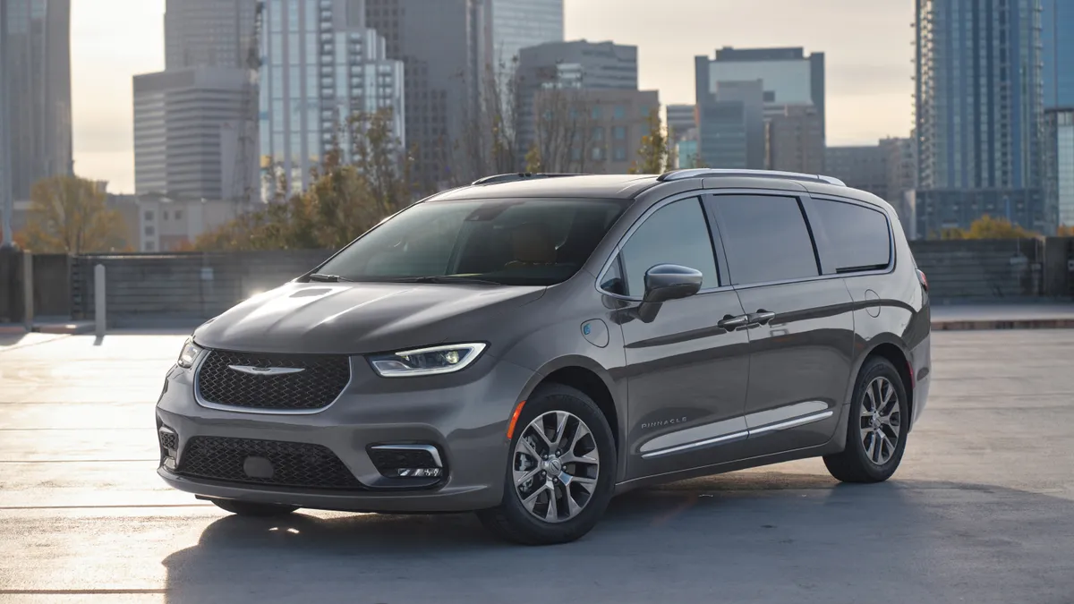 The 2024 Chrysler Pacifica hybrid minivan parked outdoors with buildings in the background.