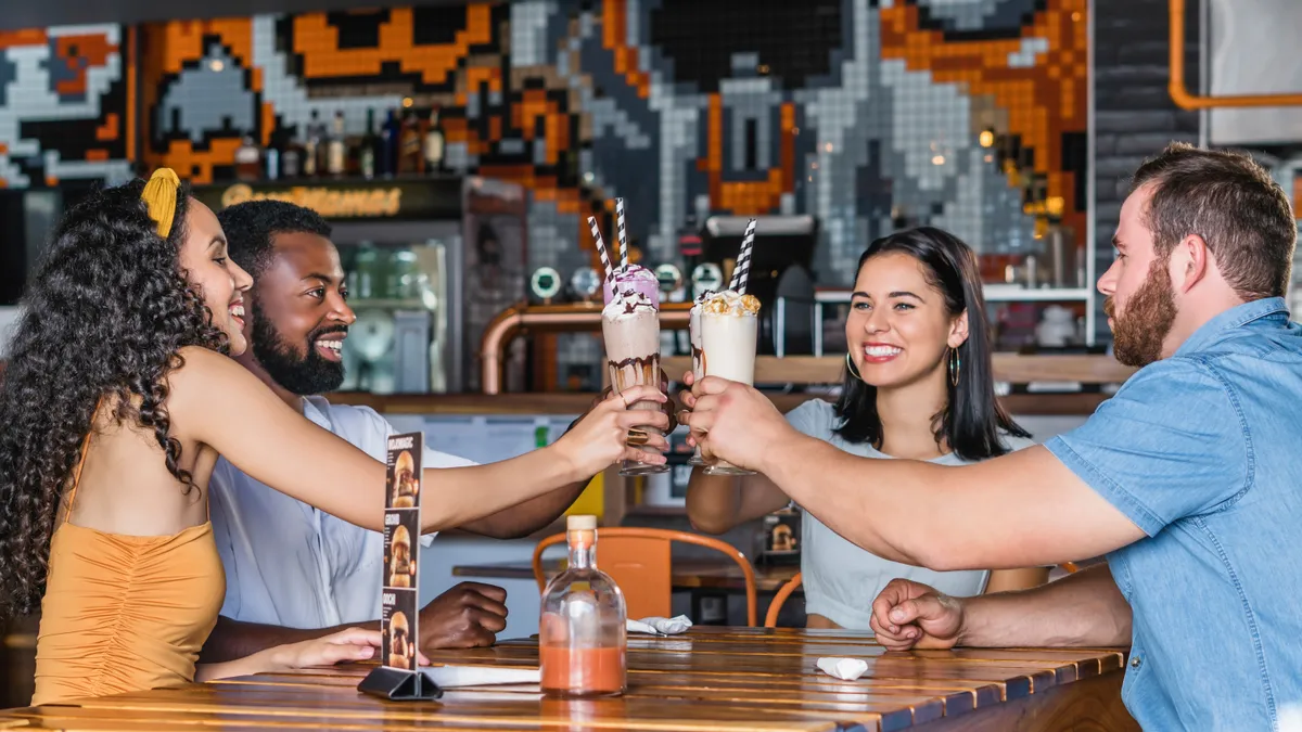 Shot of a group of young friends enjoying delicious milkshakes at a diner