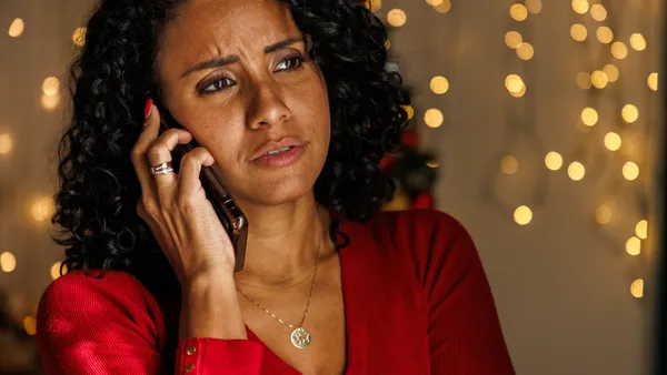 A customer on the phone with holiday lights in the background.