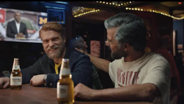 Two friends sit at a bar enjoying bottles of Modelo.