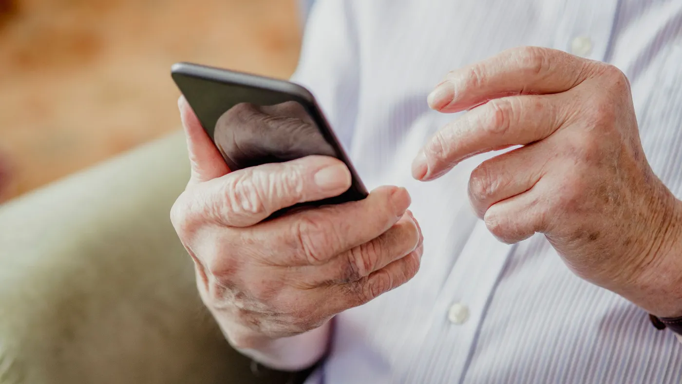 A close-up shot of an older person holding a mobile phone.