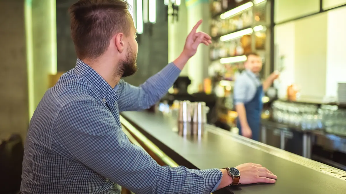 man at a bar reaching out for service