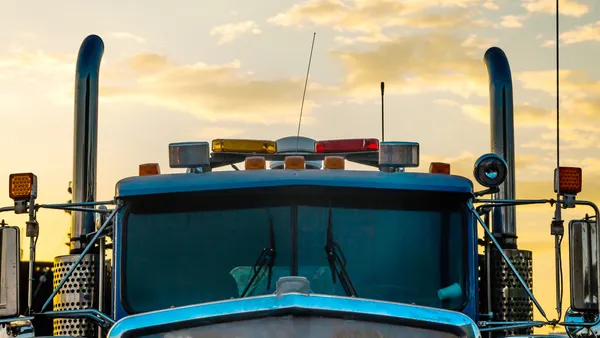 Cabin of a large heavy truck with exhaust pipes against the backdrop of a sunset